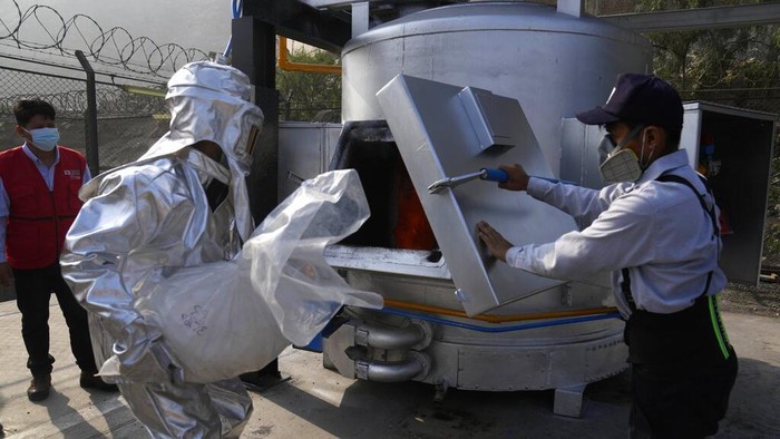 A worker tests seized cocaine to be destroyed by fire at a police base in Lima, Peru, Monday, April 18, 2022. Police say they will destroy about 16 tons of drugs seized over the past four months, including cocaine, marijuana, opium and ecstasy. (AP Photo/Martin Mejia)