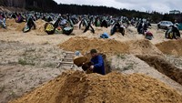 Seorang pria menggali tanah untuk membuat makam baru bagi warga yang menjadi korban invasi Rusia.