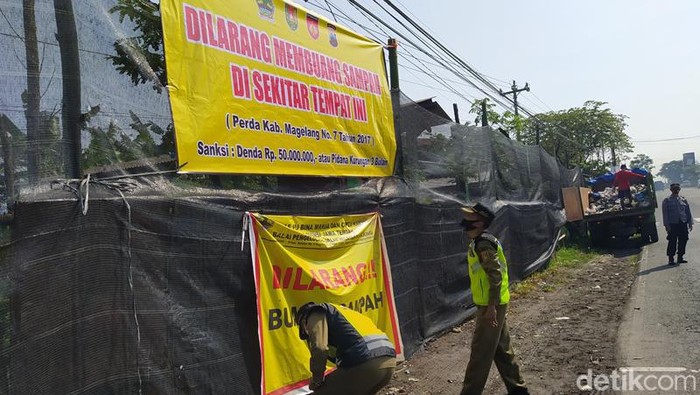 Petugas memasang spanduk larangan membuang sampah di Tempuran, Kabupaten Magelang, Selasa (19/4/2022).