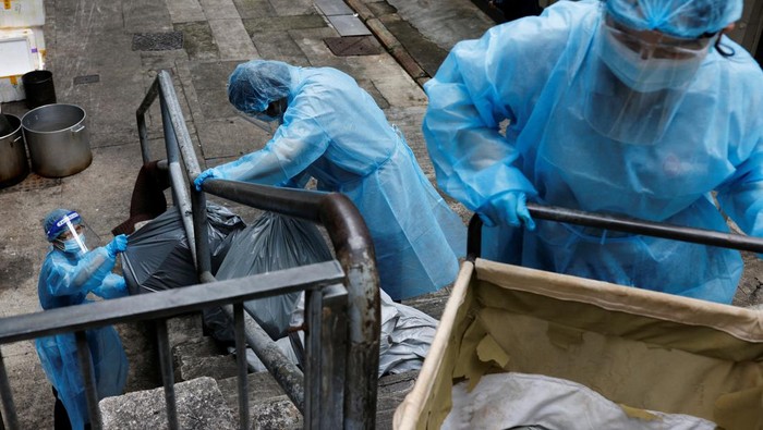 A cleaner wearing personal protective equipment (PPE) dumps garbage outside a quarantine hotel during the coronavirus disease (COVID-19) pandemic, in Hong Kong, China, April 2, 2022. Picture taken April 2, 2022. REUTERS/Tyrone Siu