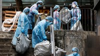 Petugas kebersihan yang mengenakan alat pelindung diri (APD) membuang sampah di luar hotel karantina selama pandemi penyakit virus corona (COVID-19), di Hong Kong, China, Selasa (19/4/2022).