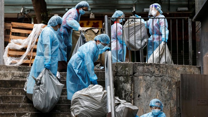 A cleaner wearing personal protective equipment (PPE) dumps garbage outside a quarantine hotel during the coronavirus disease (COVID-19) pandemic, in Hong Kong, China, April 2, 2022. Picture taken April 2, 2022. REUTERS/Tyrone Siu
