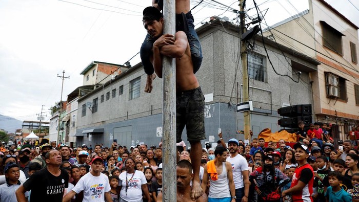 Children participate in a greasy pole game during the traditional burning of Judas, as part of the Holy Week celebrations in Caracas, Venezuela April 17, 2022. REUTERS/Leonardo Fernandez Viloria     TPX IMAGES OF THE DAY