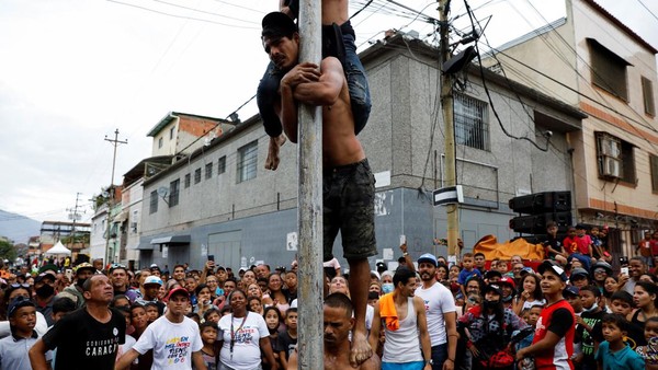 Sejumlah pria berpartisipasi dalam permainan memanjat tiang berminyak selama tradisi pembakaran Yudas, sebagai bagian dari perayaan Pekan Suci di Caracas, Venezuela (17/4/2022).