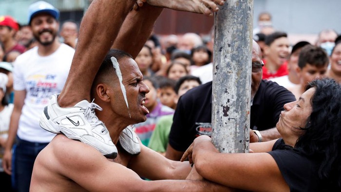 Children participate in a greasy pole game during the traditional burning of Judas, as part of the Holy Week celebrations in Caracas, Venezuela April 17, 2022. REUTERS/Leonardo Fernandez Viloria     TPX IMAGES OF THE DAY