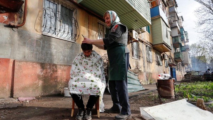 UKRAINE-CRISIS/MARIUPOL A local resident has his hair cut in a courtyard in the course of Ukraine-Russia conflict in the southern port city of Mariupol, Ukraine April 18, 2022. REUTERS/Alexander Ermochenko