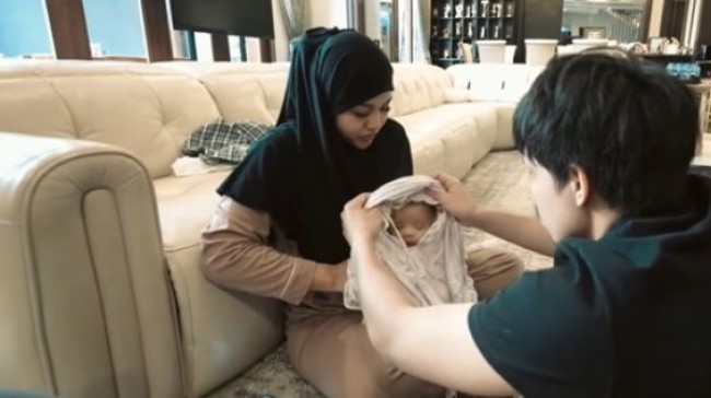 Baru-baru ini Atta Halilintar dan Aurel Hermansyah tampak membagikan momen saat putri kecil mereka belajar mengenakan hijab. Momen tersebut dibagikan ke akun YouTube AH. Terlihat jika baby Ameena awalnya sempat menolak. Foto: YouTube/AH