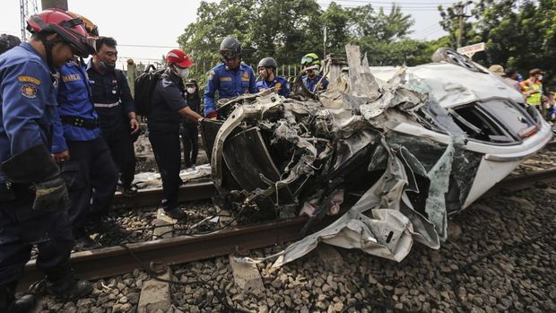 Sebuah mobil ringsek usai tertabrak KRL di kawasan Rawageni, Cipayung, Depok. Dengan bantuan alat berat, sejumlah petugas mengevakuasi mobil ringsek tersebut.