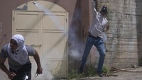Pemuda Palestina mencoba melempar balik gas air mata yang ditembakkan polisi perbatasan Israel, di Desa Burqa, Tepi Barat, Selasa (19/4/2022). Situasi di Palestina memanas dalam beberapa hari terakhir usai peristiwa di Gaza.
