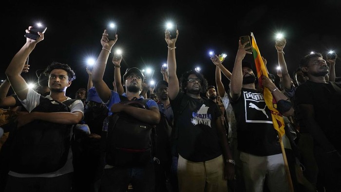 Sri Lankans hold up their mobile phone torches during a vigil condemning police shooting at protesters in Rambukkana, 90 kilometers (55 miles) northeast of Colombo, at a protest outside the president's office in Colombo, Sri Lanka, Tuesday, April 19, 2022. Sri Lankan police opened fire Tuesday at a group of people protesting new fuel price increases, killing one and injuring 10 others, in the first shooting by security forces during weeks of demonstrations over the country's worst economic crisis in decades. (AP Photo/Eranga Jayawardena)