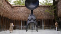 Orang-orang berdiri di sebelah patung Satelit bagian dari instalasi Kedaulatan karya seniman Simone Leigh, di paviliun Amerika Serikat. Dalam Venice Bienalle akan ada beberapa pertunjukan: pameran utama yang dikurasi, paviliun dari berbagai negara, dan pameran independen seluruh Venidia.