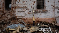 Penampakan sebuah salib bersandar di dinding gereja yang hancur imbas perang Rusia-Ukraina di Lukashivka, Ukraina, Minggu (10/4/2022). (Anastasia Vlasova/Getty Images).