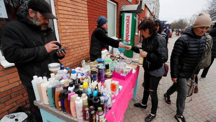 Local residents wait for their devices to be charged from a portable generator at a local market during Ukraine-Russia conflict in the southern port city of Mariupol, Ukraine April 19, 2022. REUTERS/Alexander Ermochenko