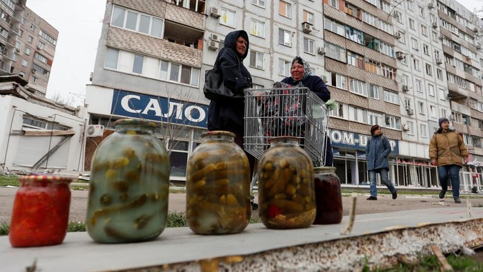 Local residents wait for their devices to be charged from a portable generator at a local market during Ukraine-Russia conflict in the southern port city of Mariupol, Ukraine April 19, 2022. REUTERS/Alexander Ermochenko