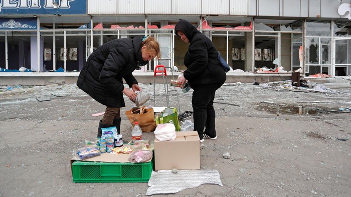 Local residents wait for their devices to be charged from a portable generator at a local market during Ukraine-Russia conflict in the southern port city of Mariupol, Ukraine April 19, 2022. REUTERS/Alexander Ermochenko