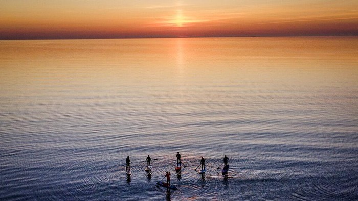 Paddle boarders tour the calm Baltic Sea in Timmendorfer Strand northern Germany as the sun rises on a cold Monday, morning, April 18, 2022. (AP Photo/Michael Probst)