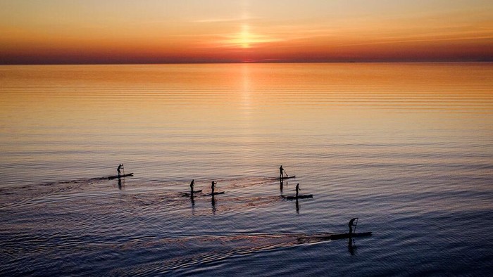 Paddle boarders tour the calm Baltic Sea in Timmendorfer Strand northern Germany as the sun rises on a cold Monday, morning, April 18, 2022. (AP Photo/Michael Probst)