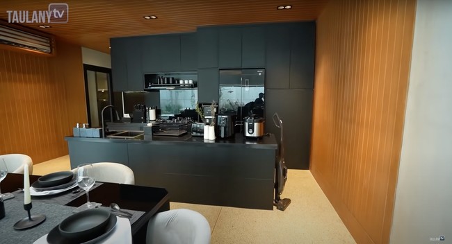 Bagian dapurnya tampak didominasi warna hitam. Sebagian besar peralatannya pun tampak berwarna hitam. Uniknya, salah satu lemari dapur itu merupakan pintu menuju ke ruang penyimpanan yang cukup luas. Foto: YouTube/Taulany TV