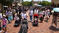 Pengunjung mengenakan masker berjalan di Hong Kong Disneyland.