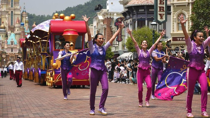 Visitors take photographs of cartoon characters during a parade at the Hong Kong Disneyland, Thursday, April 21, 2022. Hong Kong Disneyland reopened to the public after shutting down due to a surge in COVID-19 infections. (AP Photo/Kin Cheung)