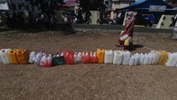 Seorang warga melintas di deretan jerigen yang diletakkan warga saat antre untuk mendapatkan minyak goreng curah yang didistribusikan pada gelaran pasar murah di Palu, Sulawesi Tengah, Kamis (21/4/2022).