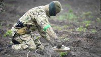 Seorang pencari dari kementerian dalam negeri menjinakkan ranjau setelah pertempuran baru-baru ini di Irpin dekat dengan Kiev, Ukraina, Selasa, (19/4/2022).