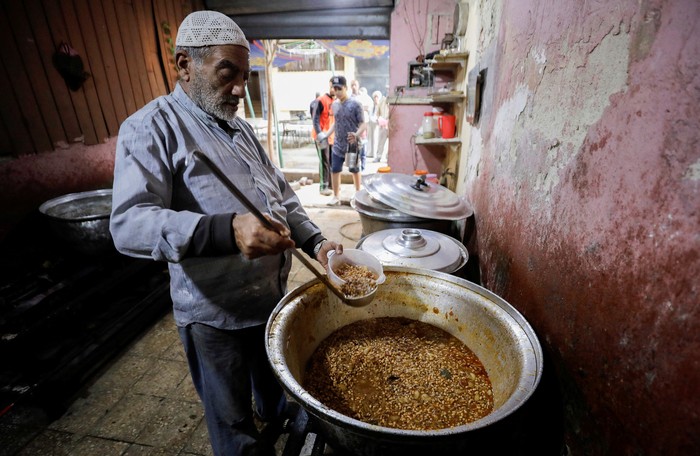 RELIGION-RAMADAN/EGYPT-FOOD DISTRIBUTION People queue to get prepared food to eat during Iftar, a meal to end their fast at sunset, during a distribution organised by Gameel Kamal (not pictured), a 76-year-old Christian man who says he has been distributing food during the holy fasting month of Ramadan for the last 40 years, in Cairo, Egypt April 20, 2022. Picture taken April 20, 2022. REUTERS/Mohamed Abd El Ghany