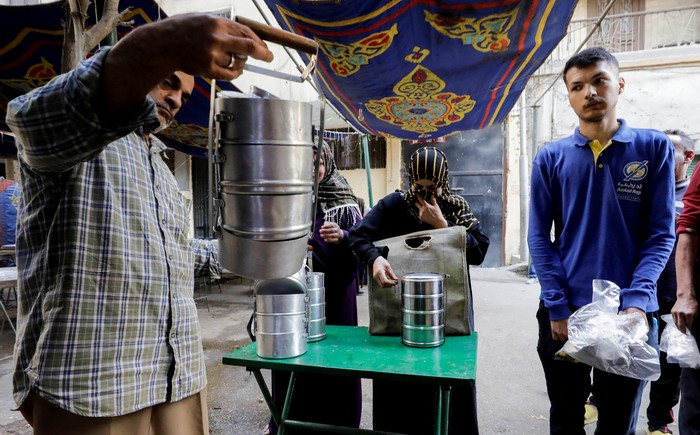 People queue to get prepared food to eat during Iftar, a meal to end their fast at sunset, during a distribution organised by Gameel Kamal (not pictured), a 76-year-old Christian man who says he has been distributing food during the holy fasting month of Ramadan for the last 40 years, in Cairo, Egypt April 20, 2022. Picture taken April 20, 2022. REUTERS/Mohamed Abd El Ghany