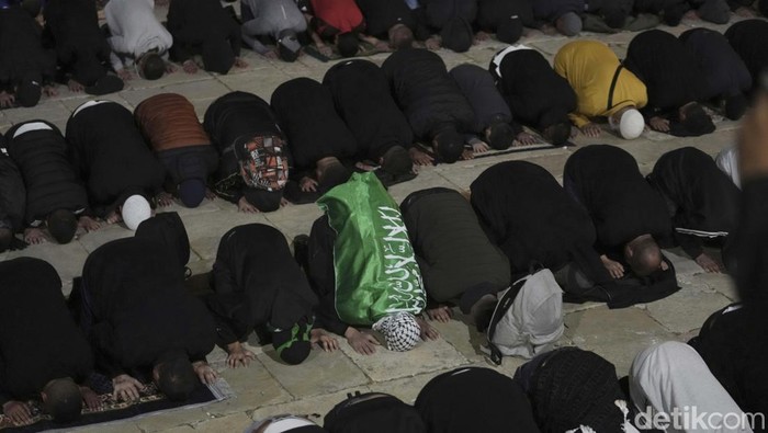 Palestinians gather for morning prayer during the Muslim holy month of Ramadan, shortly before Israeli police clashed with protesters at the Al Aqsa Mosque compound, in Jerusalem's Old City, Friday, April 22, 2022. Israeli police and Palestinian youths clashed again at the major Jerusalem holy site sacred to Jews and Muslims on Friday despite a temporary halt to Jewish visits to the site, which are seen as a provocation by the Palestinians. (AP Photo/Mahmoud Illean)