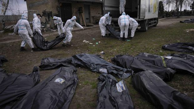 Volunteers load bodies of civilians killed in Bucha onto a truck to be taken to a morgue for investigation, in the outskirts of Kyiv, Ukraine, Tuesday, April 12, 2022. (AP Photo/Rodrigo Abd)