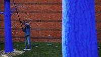Seorang sukarelawan mewarnai pohon menjadi biru di luar Museum Peabody Essex, di Salem, Massachusetts, Amerika Serikat, Kamis (21/4/2022). Cat tersebut diklaim ramah lingkungan. 