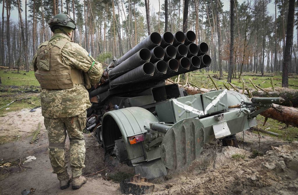 A Ukrainian soldier examines Russian multiple missiles system abandoned by Russian troops in the village of Berezivka, Ukraine, Thursday, April 21, 2022. Writing on the missiles reads 