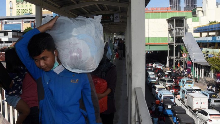 Pejalan kaki membawa barang belanjaan di tengah kemacetan kawasan Pasar Tanah Abang, Jakarta, Sabtu (23/4/2022). Kemacetan terjadi akibat membludaknya pengunjung yang berbelanja kebutuhan Lebaran di pasar tersebut. ANTARA FOTO/Indrianto Eko Suwarso/rwa.