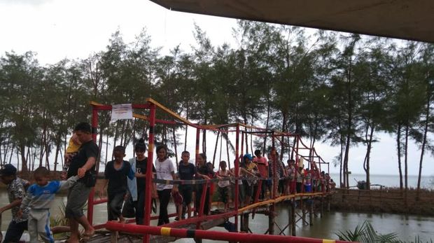 Sejumlah pengunjung melintasi titi kayu di Pantai Somi, Kabupaten Nias.