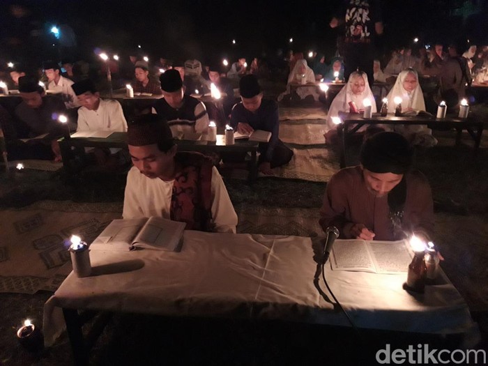 Santri Ponpes Nurul Hidayah mengaji di alam terbuka dengan penerangan lampu sentir.
