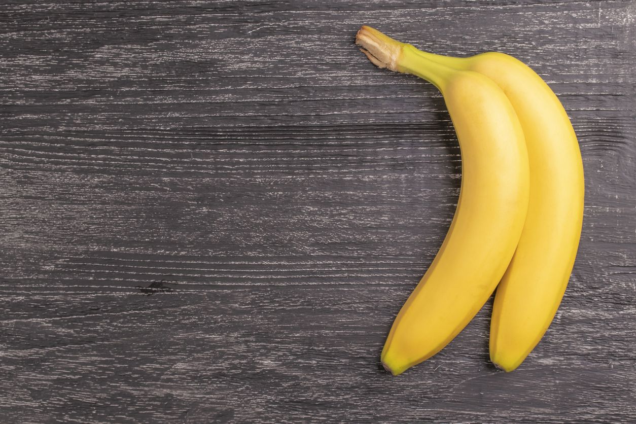 Two ripe yellow bananas on the old rough scratched wooden boards background surface. Top view