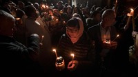 Jemaat Ortodoks memegang lilin saat kebaktian Paskah di Gereja Paroki Brancusi di Bucharest, Rumania, Minggu, 24 April 2022.