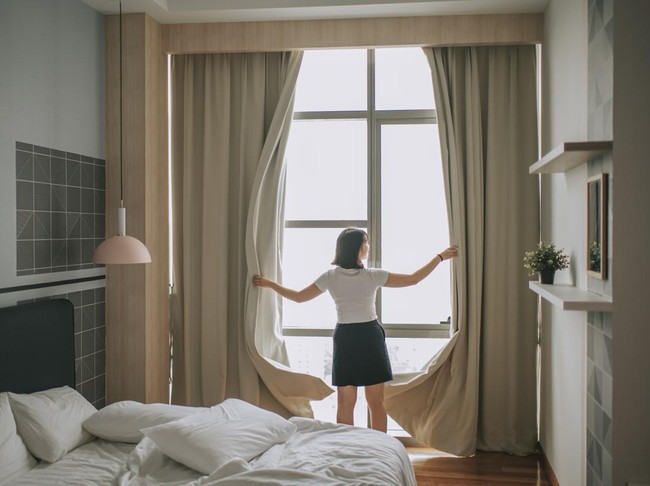 rear view asian chinese teenage girl open curtain of her bedroom in the morning