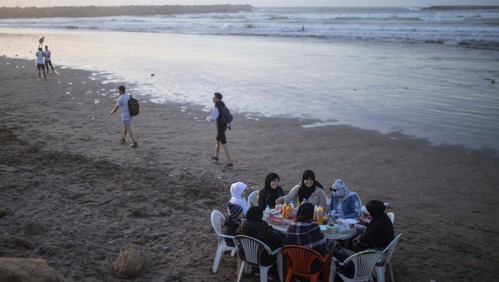 A family pose for a photo as they break their Ramadan fast by the beach in Rabat, Morocco, Saturday, April 23, 2022. For the first time in two years since the COVID-19 pandemic, people were able to revive a Ramadan tradition of gathering and breaking their fast in public. (AP Photo/Mosa'ab Elshamy)