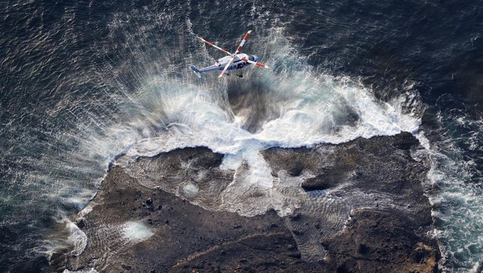 An aerial view shows a Japan Coast Guard helicopter conducts a search and rescue operations for missing people boarded on the missing tour boat 