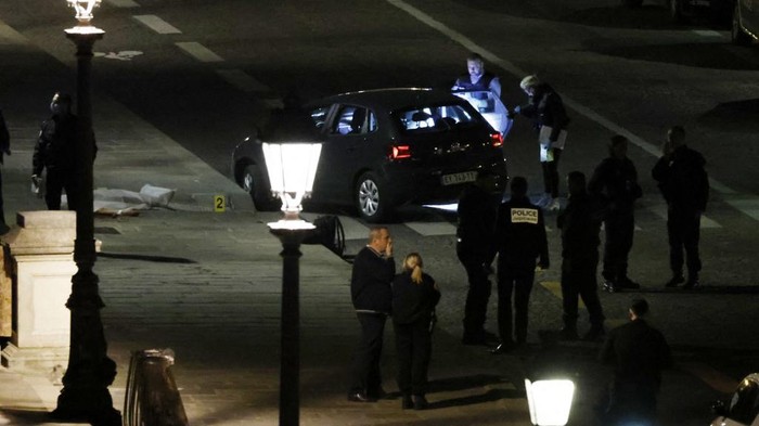 Police officers investigate the car driven by two people who were shot by police in Paris on April 25, 2022. - Shortly after midnight on Sunday night, police opened fire on a car that refused to stop at a police checkpoint on the Pont Neuf in Paris. Police told AFP the car was driving against traffic and sped towards officers, who were forced to open fire, according to the same police source. (Photo by Ludovic MARIN / AFP)