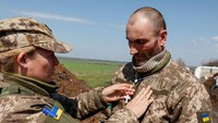 Prajurit Ukraina membantu rekannya untuk menyesuaikan rosario di lehernya yang disajikan oleh pendeta militer setelah kebaktian Paskah Ortodoks.