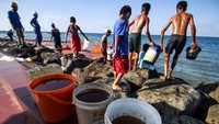 Warga mengambil minyak solar yang tumpah dari kapal penggangkut Bahan Bakar Minyak (BBM) di Pelabuhan Depot Pertamina Desa Hagu Selatan, Lhokseumawe, Aceh, Minggu (24/4). Depot PT Pertamina Regional II Lhokseumawe masih melakukan investigasi penyebab terjadinya tumpahan solar dari kapal berlambung Masbos Diaz tersebut.     