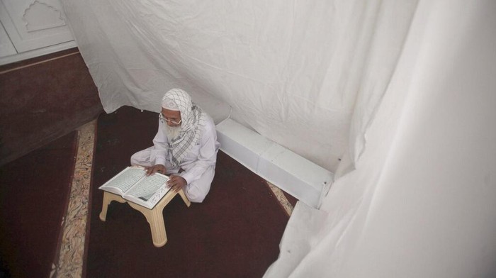 A Muslim worshipper recites from the Quran in his section while he observes Itikaf which requires staying in seclusion in a mosque to read the holy book and pray during the last ten days of the Islamic fasting on month of Ramadan, at a mosque, in K