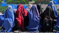 Perempuan mengenakan baju yang tertutup saat mengantre bantuan.