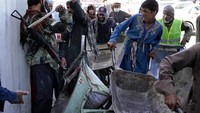 Pejuang Taliban menenteng senjata saat menertibkan antrean paket lebaran.