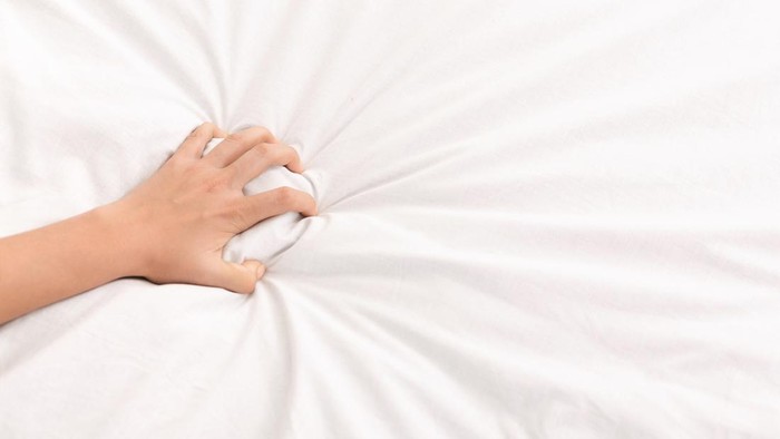 Ecstasy. Female hand grasping white crumpled bed sheet, feeling sexual pleasure or orgasm, panorama, copy space