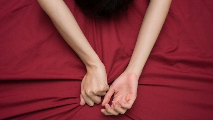 Ilustrasi Orgasme pada Wanita hand grasping on bed sheet