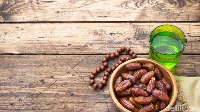 Dried dates fruits and a glass of water on a wooden table. Traditional fast breaking, Muslims evening meal during holy Ramadan