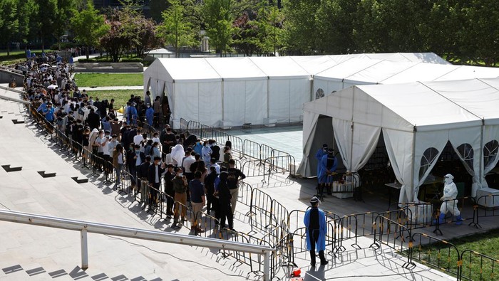 People line up outside a makeshift nucleic acid testing site during a mass testing for the coronavirus disease (COVID-19) in Haidian district of Beijing, China April 26, 2022. REUTERS/Carlos Garcia Rawlins